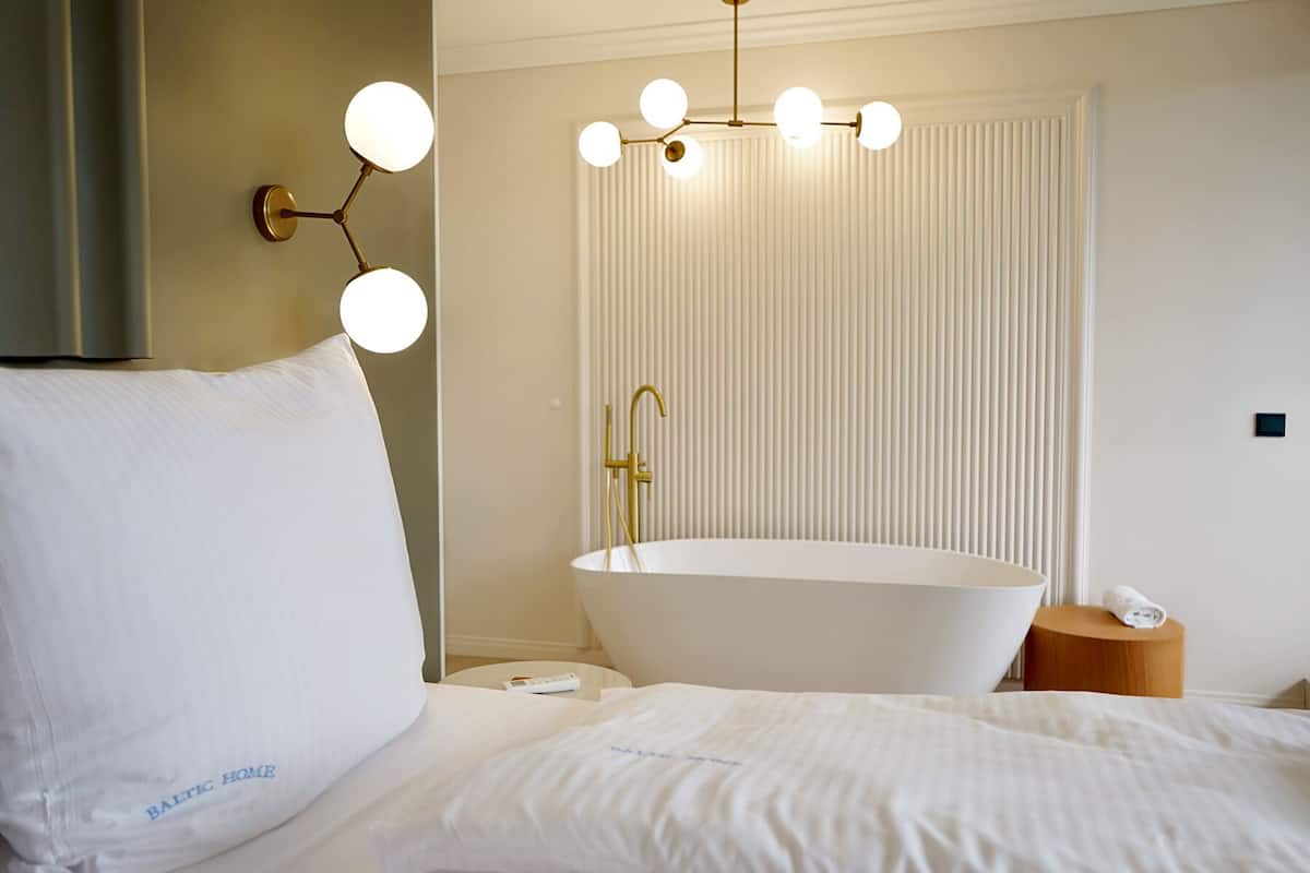 Une salle de bain moderne avec une baignoire sur pieds, un luminaire fixé au mur et un porte-serviettes.