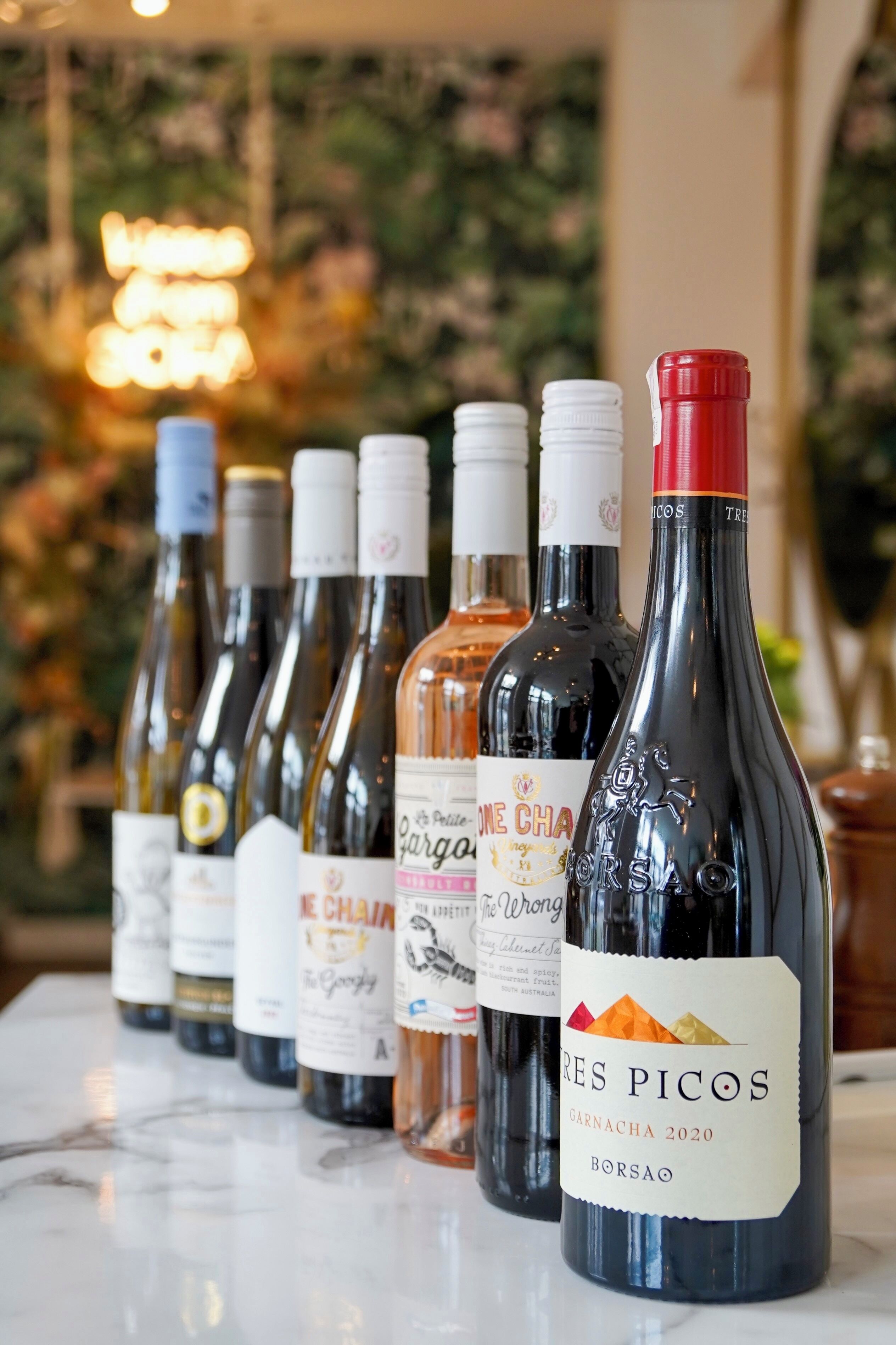 A row of wine bottles on a marble surface with a blurred background.