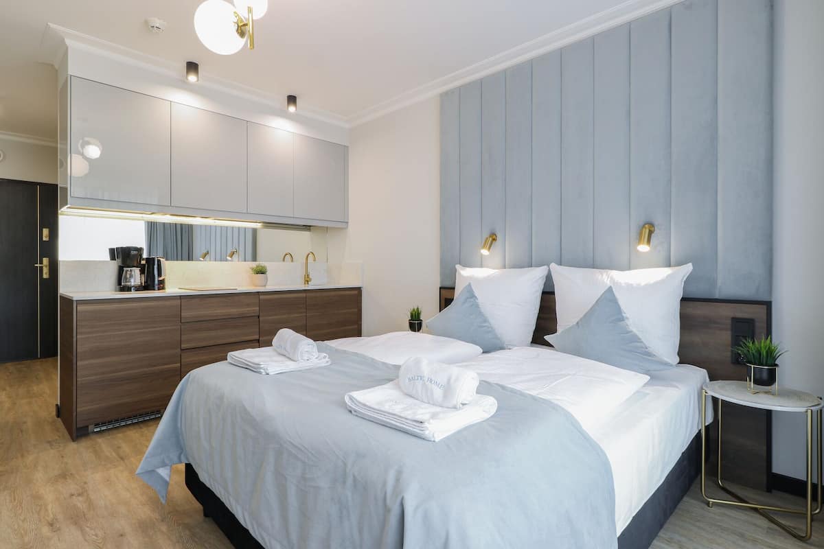 Une chambre d’hôtel moderne dotée d’un grand lit, d’un bureau intégré, d’une petite table d’appoint et d’un grand miroir.