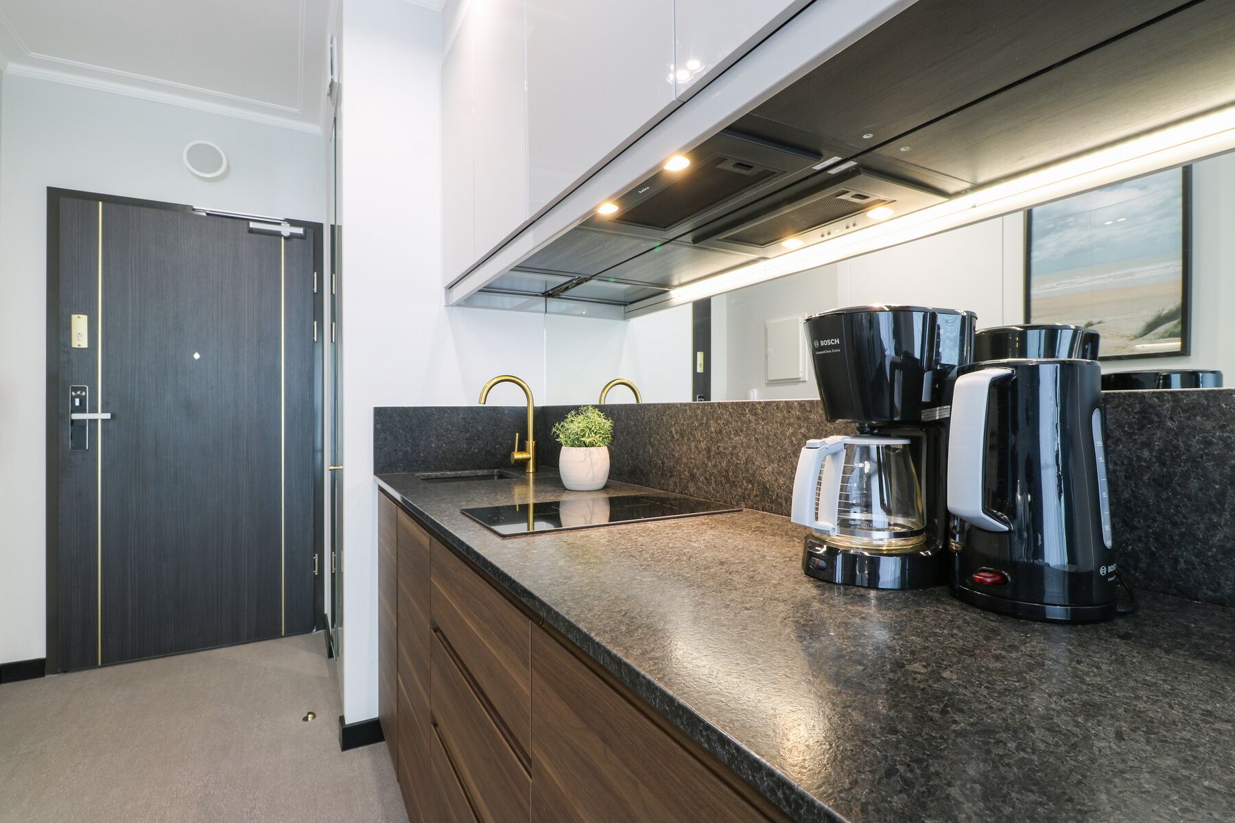 Una cocina moderna con estufa integrada, cafetera y pileta.