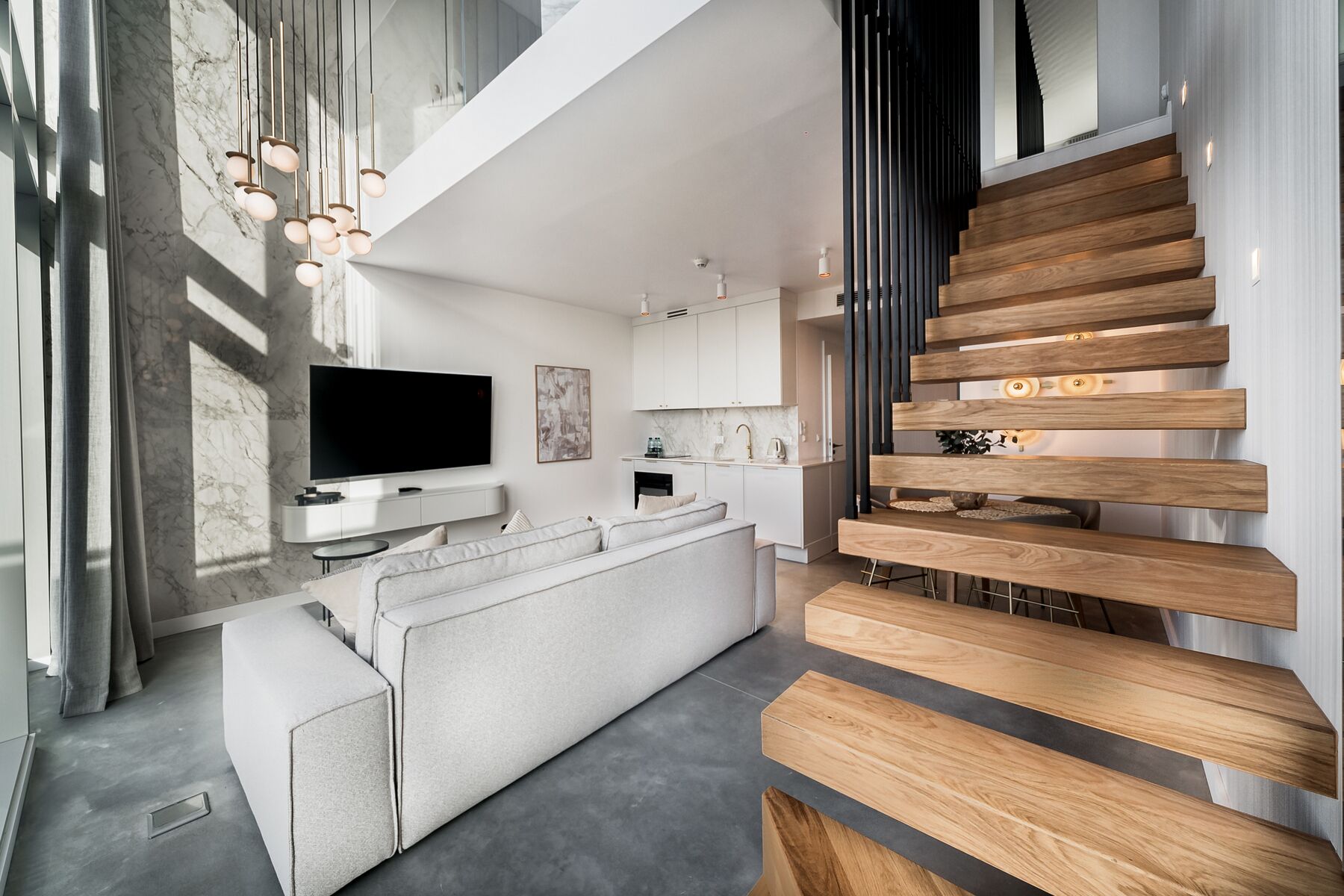 Een modern interieur met een zithoek, keuken en trap.
