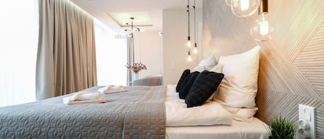 Una habitación de hotel moderna con una cama bien hecha, una mesita de noche con una planta y una pared con diseño geométrico.
