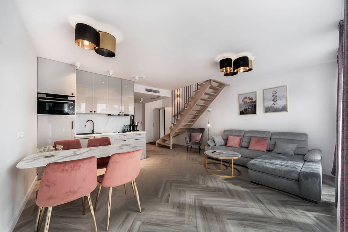 Ein moderner Wohnraum mit Küche, Essbereich und einer Treppe zu einem Schlafloft.