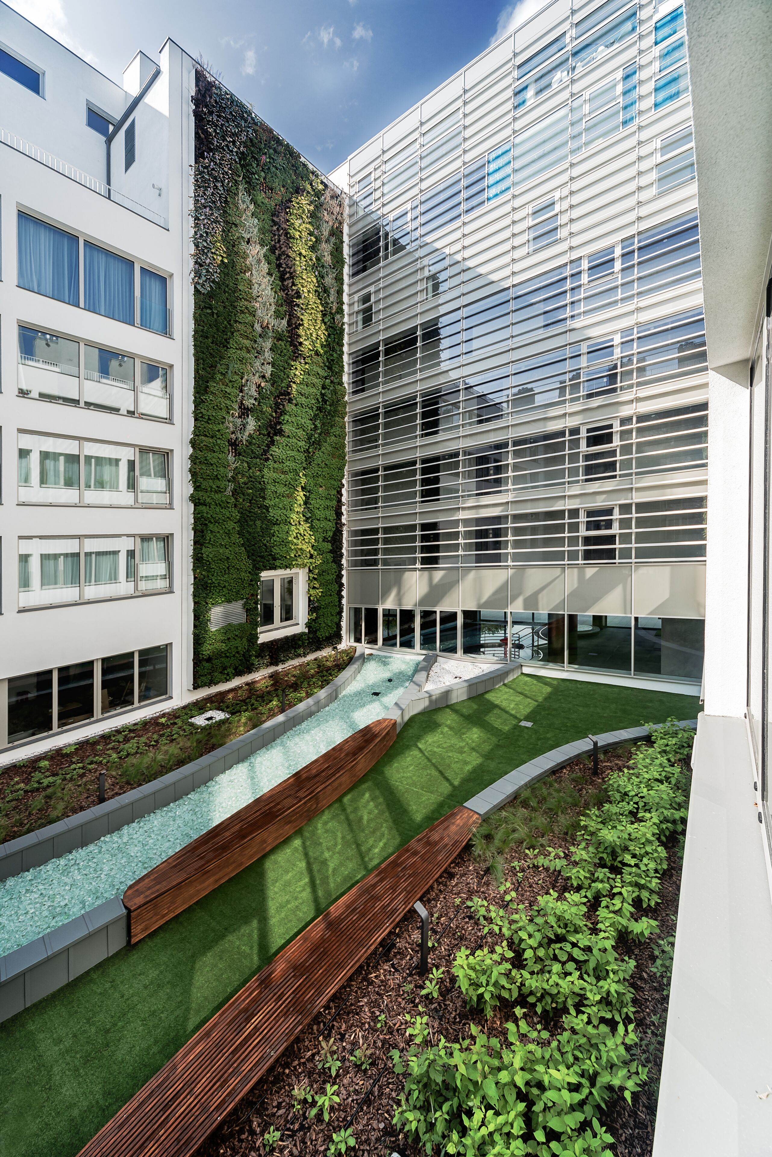 A modern building with a vertical garden, a swimming pool, and a wooden deck.
