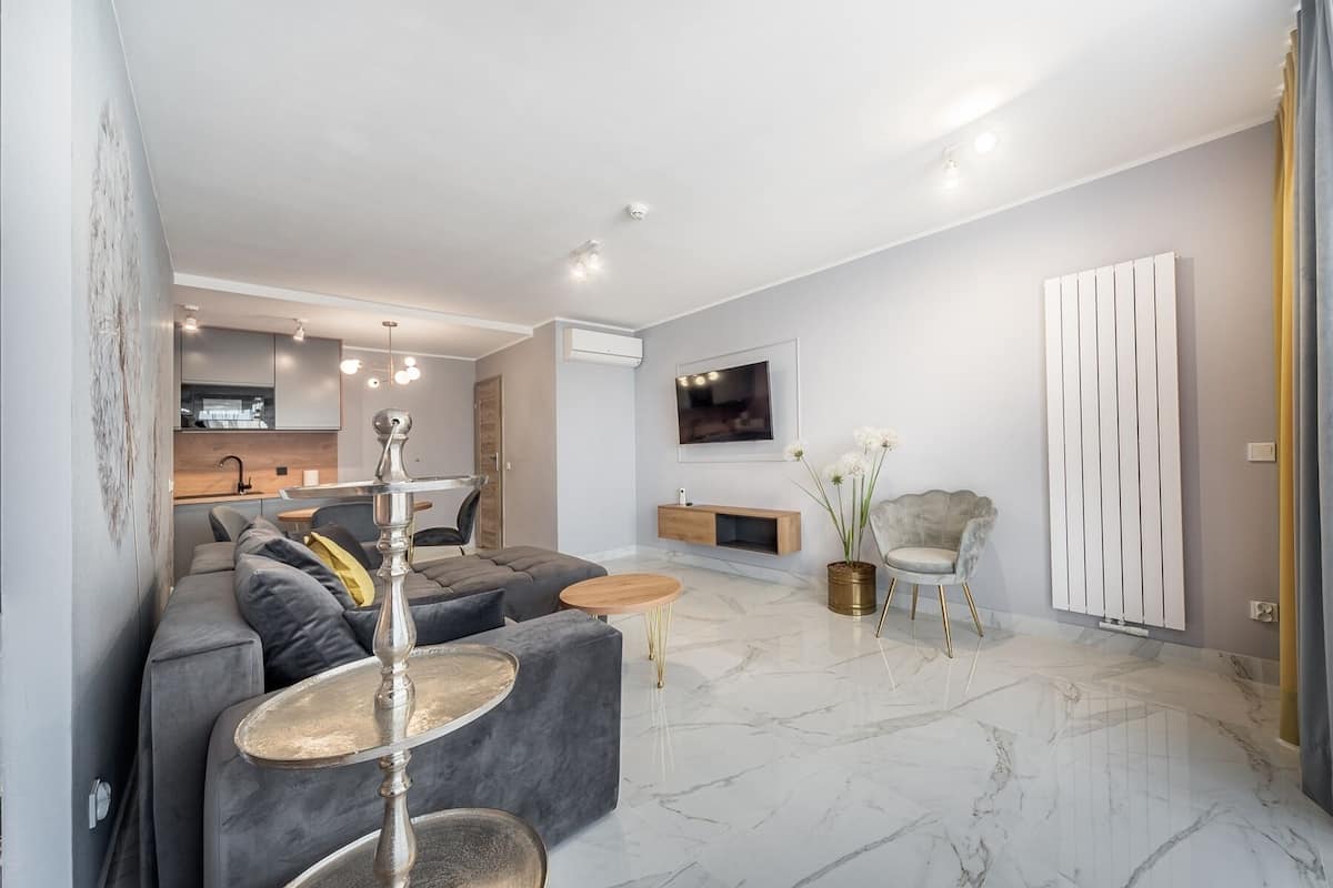 Ein modernes Wohnzimmer mit einem grauen Sofa, einem Couchtisch und einem an der Wand montierten Fernseher.