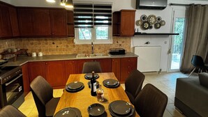 Eine moderne Küche mit Holzschränken, einem Esstisch für vier Personen und einem eingebauten Backofen.