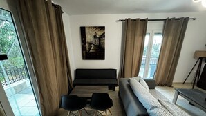 Ein modernes Wohnzimmer mit einer Couch, zwei schwarzen Sesseln, einem kleinen Tisch und einem Gemälde an der Wand.