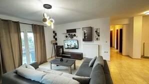 Ein modernes Wohnzimmer mit Sofa, Couchtisch und Fernseher. Eine Treppe führt zu einer weiteren Ebene.