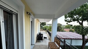 Ein Balkon mit einer Holzbank, einem Tisch und Stühlen.