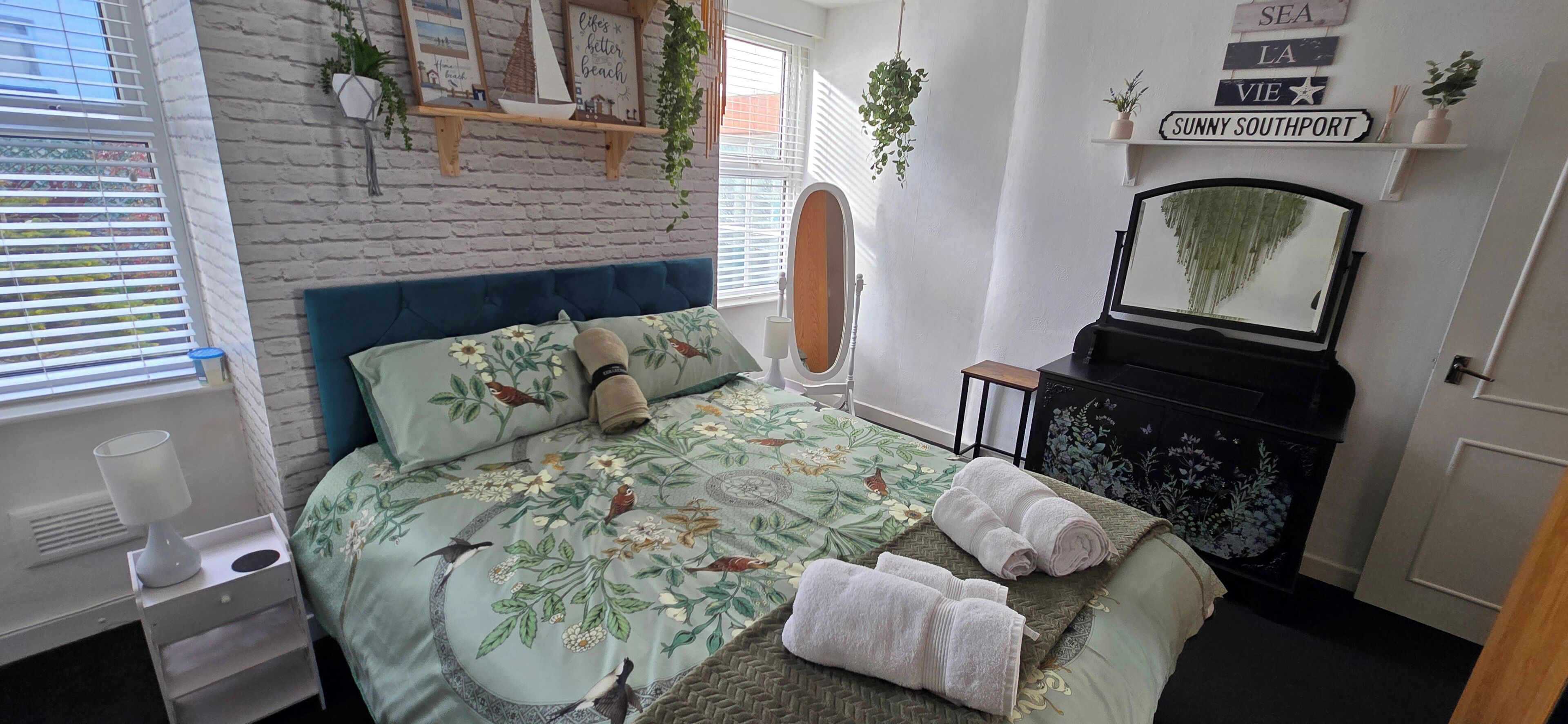 A bedroom with a bed, a dresser, a mirror, and a window with blinds.