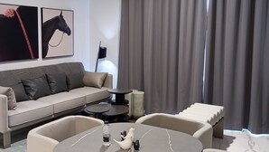 Un salon moderne avec un canapé, une table basse ronde et deux fauteuils. Deux portraits de chevaux encadrés ornent le mur.