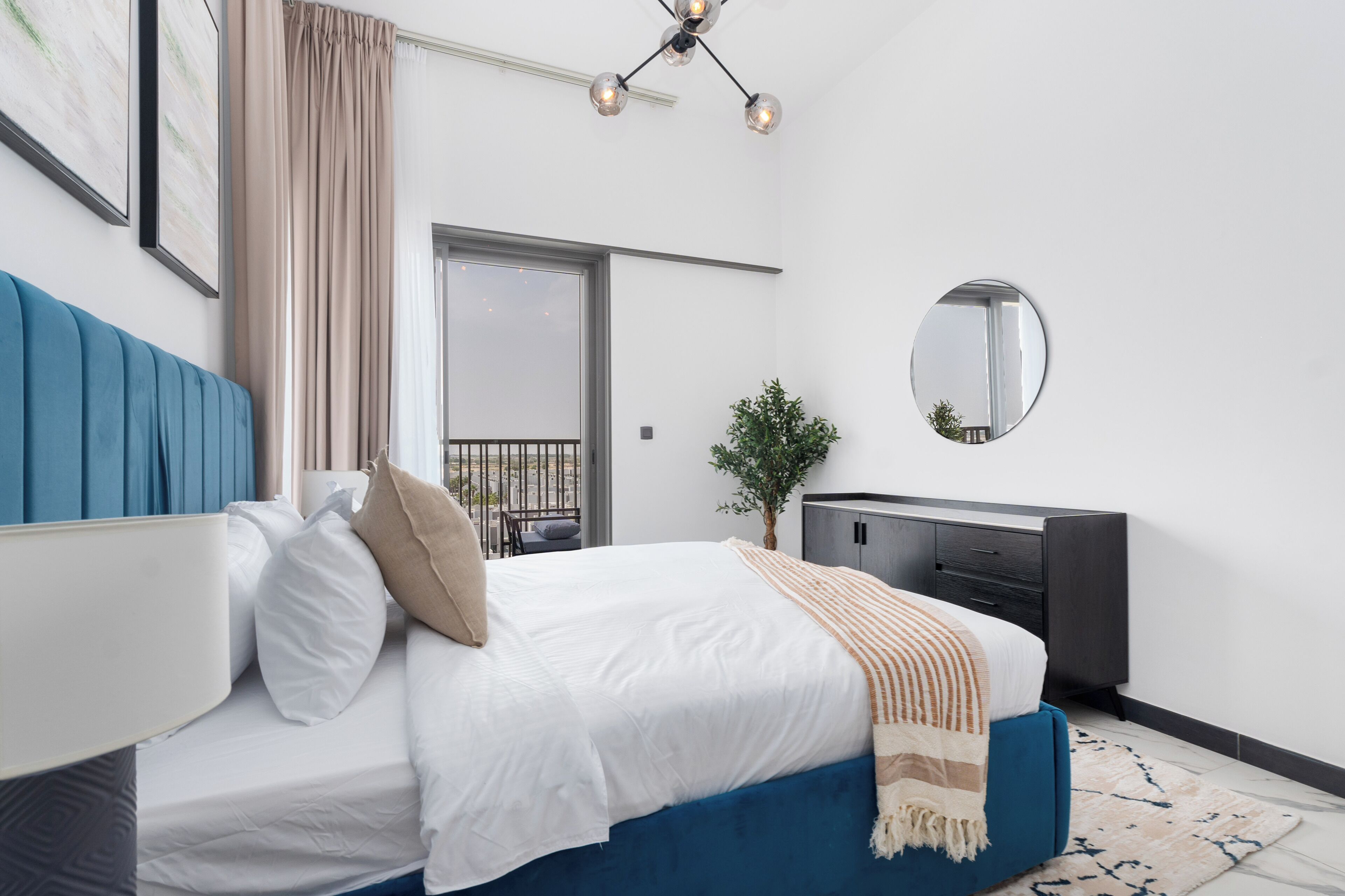 Una camera da letto moderna con un letto grande, una cassettiera, uno specchio e vista sul balcone.
