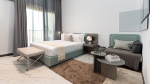 Une chambre moderne comprenant un lit, des tables de chevet, une commode et un petit coin salon.