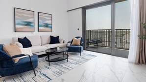Un salon moderne comprenant un canapé, deux fauteuils, une table basse et une grande porte-fenêtre coulissante donnant sur un balcon.