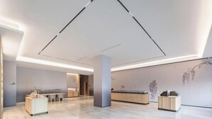 A spacious, modern hotel lobby with a minimalist design, featuring a long reception desk, a seating area, and a large, geometric light fixture on the ceiling. - JI Hotel (Wenling Wanchang Road Subway Station) (Wenling)