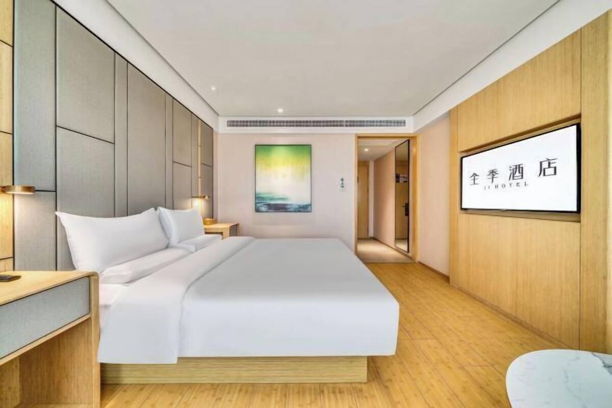 Een moderne hotelkamer met een groot bed, houten lambrisering en een lijst met een bordje aan de muur.