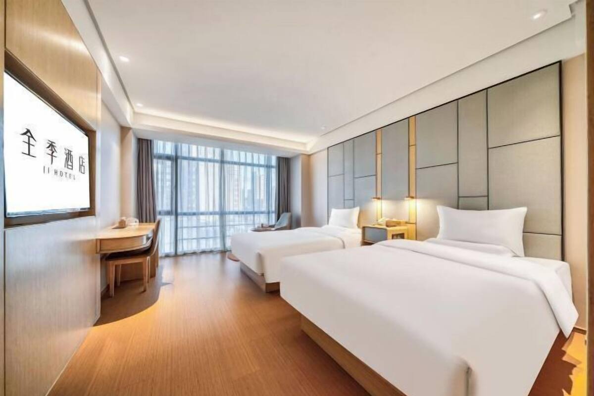 Een hotelkamer met twee bedden, een bureau en een groot raam.
