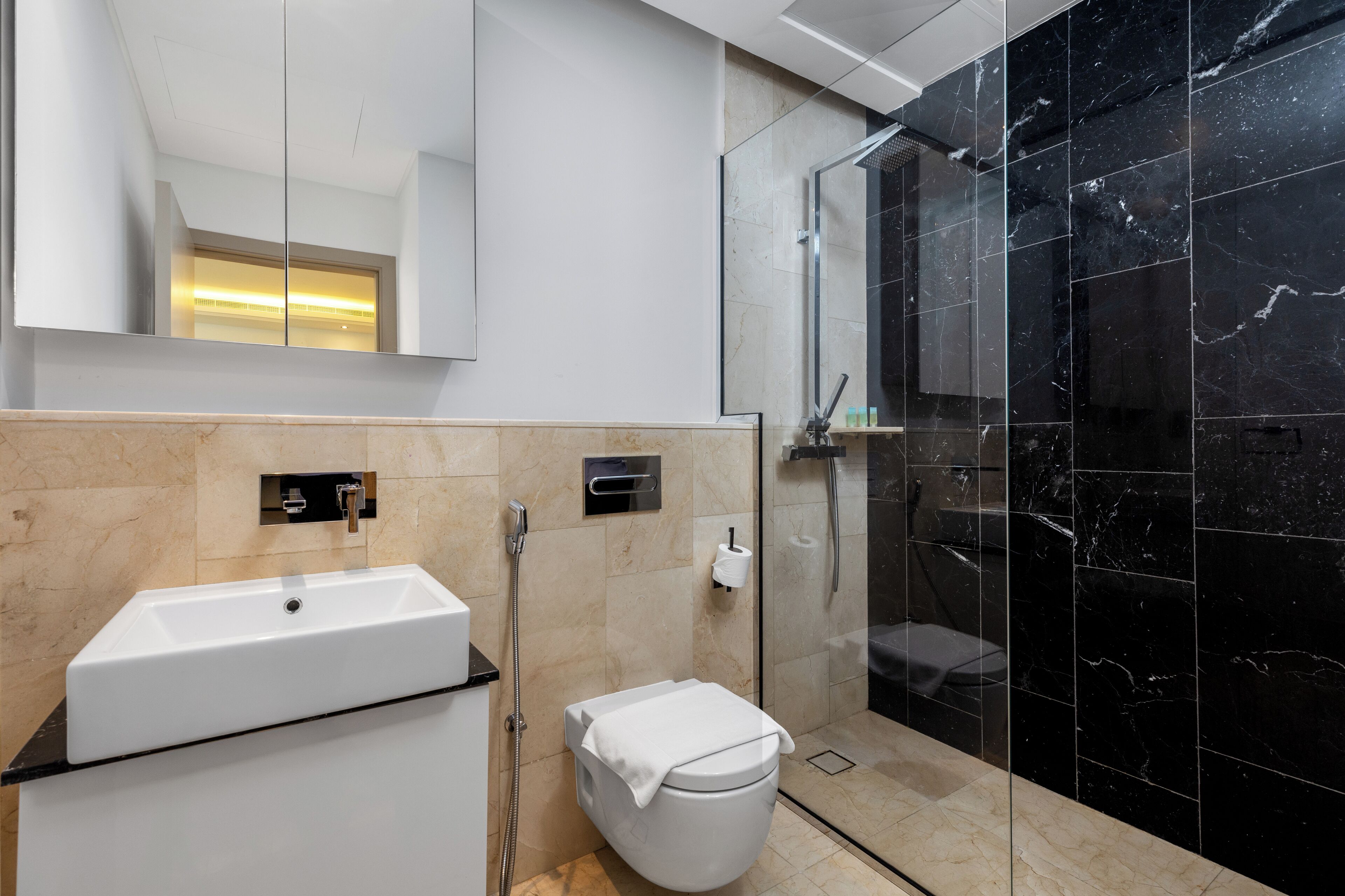 A modern bathroom with a white sink, toilet, and shower area.