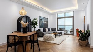 Een moderne woonkamer met een eethoek, grote ramen en uitzicht op de omgeving.