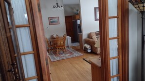 Una mesa de comedor de madera con sillas, un sofá, una lámpara y una cocina al fondo.