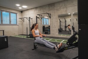 Une salle de sport équipée de matériel d’exercice, d’un rameur et d’un miroir.