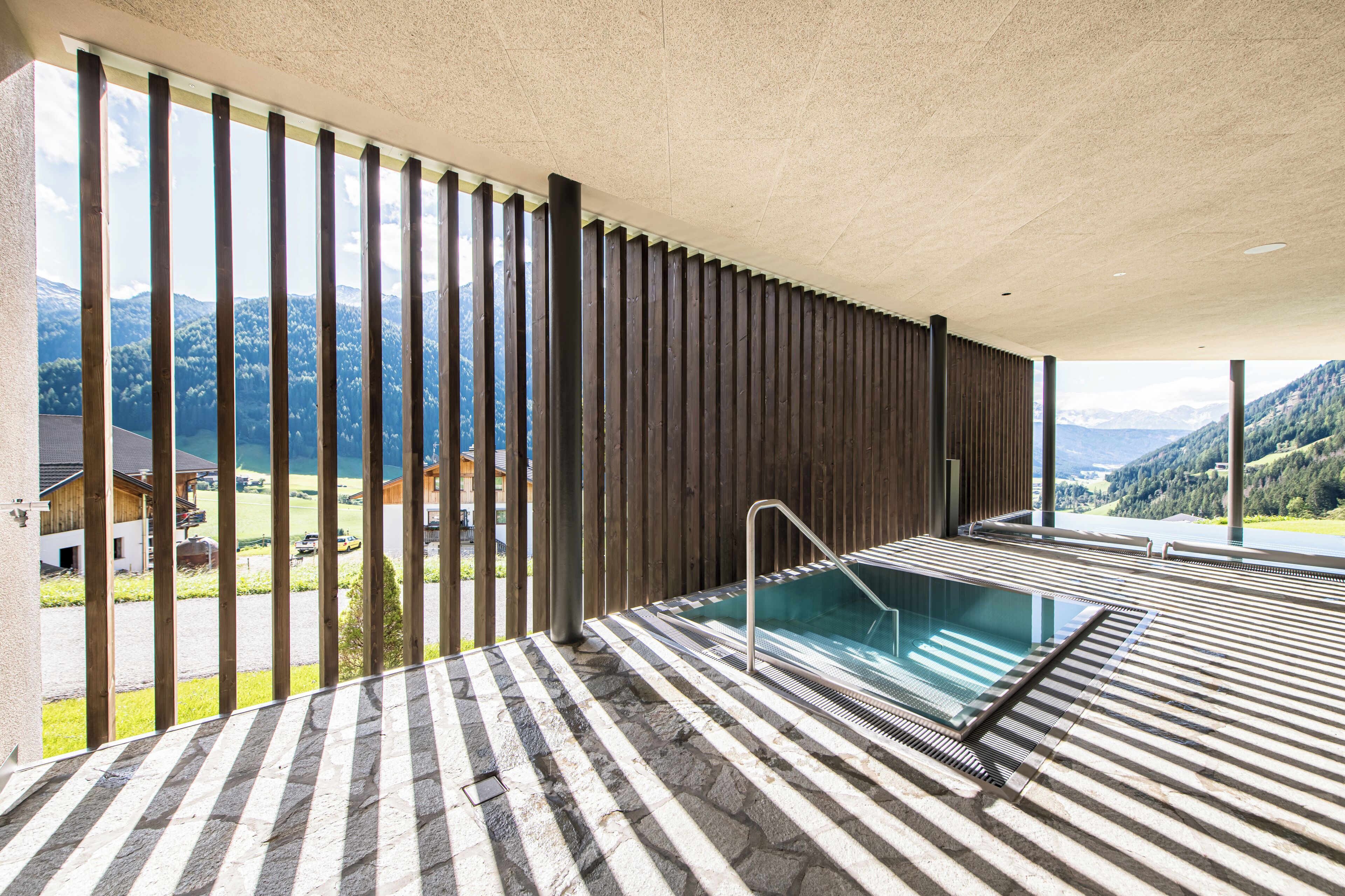 Ein Wellnessbereich mit Pool, Holzlatten und Bergblick.
