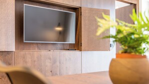 Un intérieur moderne avec un téléviseur à écran plat fixé à un mur en bois, une plante en pot et une table en bois.