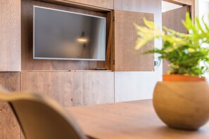 Ein modernes Interieur mit einem an einer Holzwand montierten Flachbildfernseher, einer Topfpflanze und einem Holztisch.