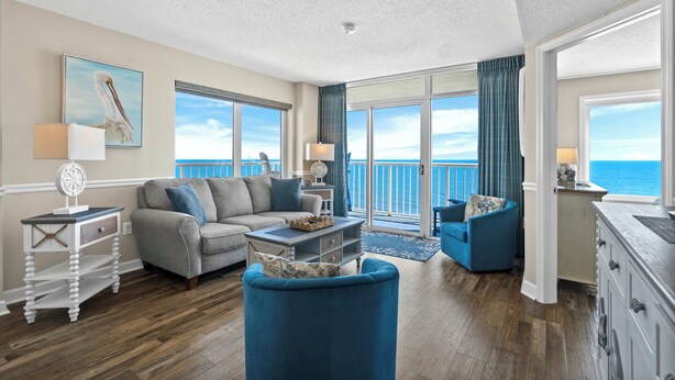 A spacious living room with a view of the ocean, a balcony with a sliding door, and a dining area with a view. - Pelican's Perch @ Seawatch (Myrtle Beach)