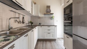 A modern kitchen with white cabinetry, stainless steel appliances, and a patterned backsplash.