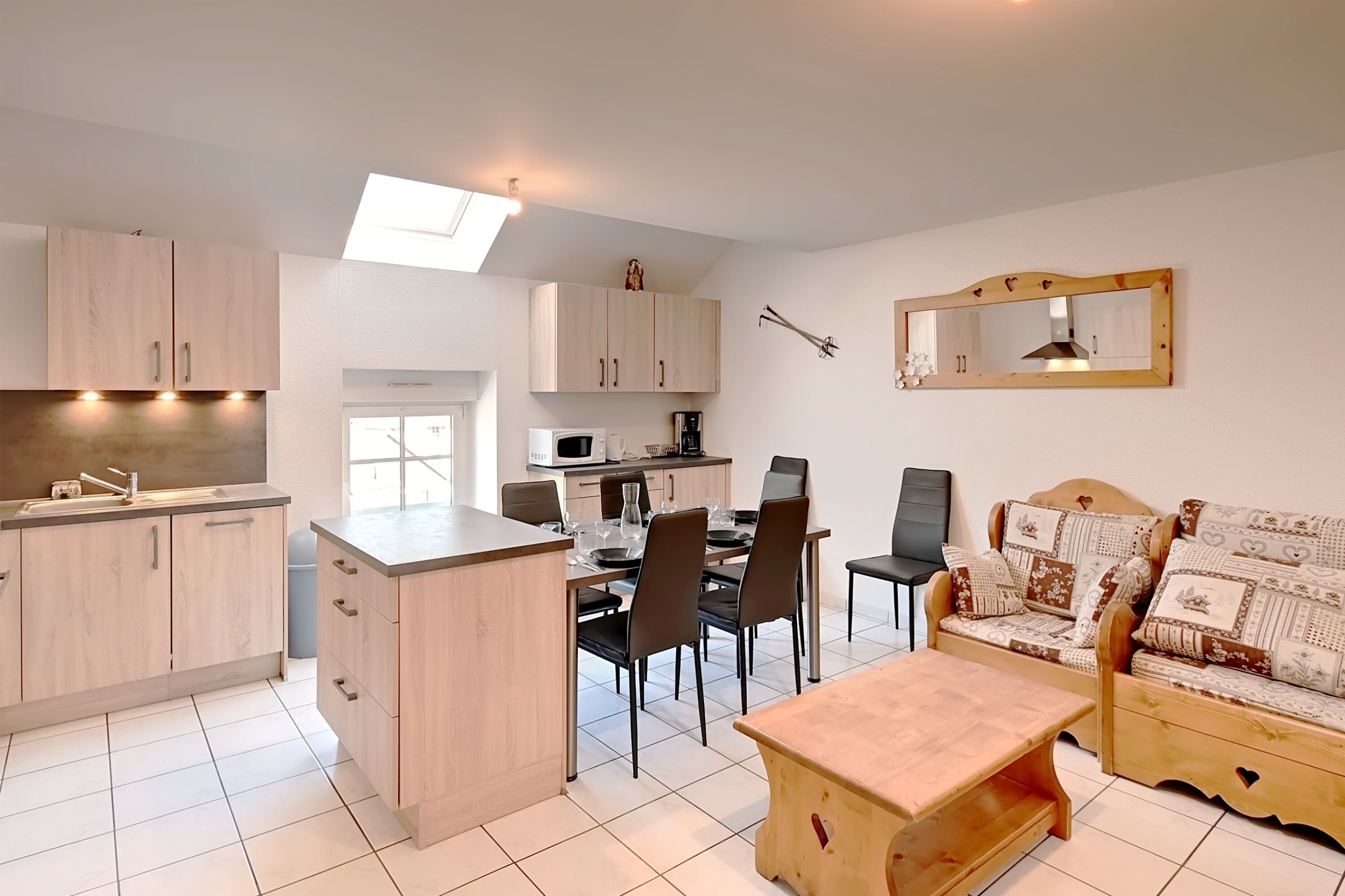 A modern kitchen with a dining area, a sofa, and a small table.