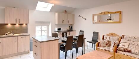 A modern kitchen with a dining area, a sofa, and a small table.