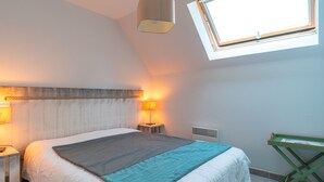 A bedroom with a bed, bedside lamps, a window, and a radiator. - Le Nid de Ker an Aod - Appt à 100m de la plage (Benodet)