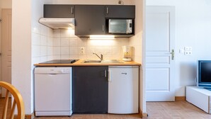 Een compacte keuken met een magnetron, spoelbak, vaatwasser en een kleine koelkast.