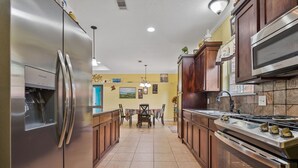 A modern kitchen with stainless steel appliances, wooden cabinets, and a tiled floor. - Tremendous Family Home on the Curve! 3-bedrooms close to the lake and amenities (Brookeland)