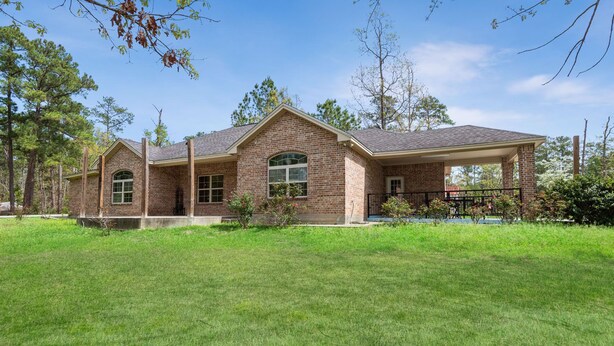 A two-story brick house with a covered patio, surrounded by a well-maintained lawn and trees. - Tremendous Family Home on the Curve! 3-bedrooms close to the lake and amenities (Brookeland)