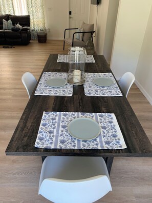 Ein Esstisch, gedeckt mit Platzsetzern, Tellern und einer Kerzenarrangements.