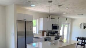 A modern kitchen with white cabinetry, stainless steel appliances, and a central island with bar stools. - Pool Heated House - Near beach in Port Charlotte (Port Charlotte)
