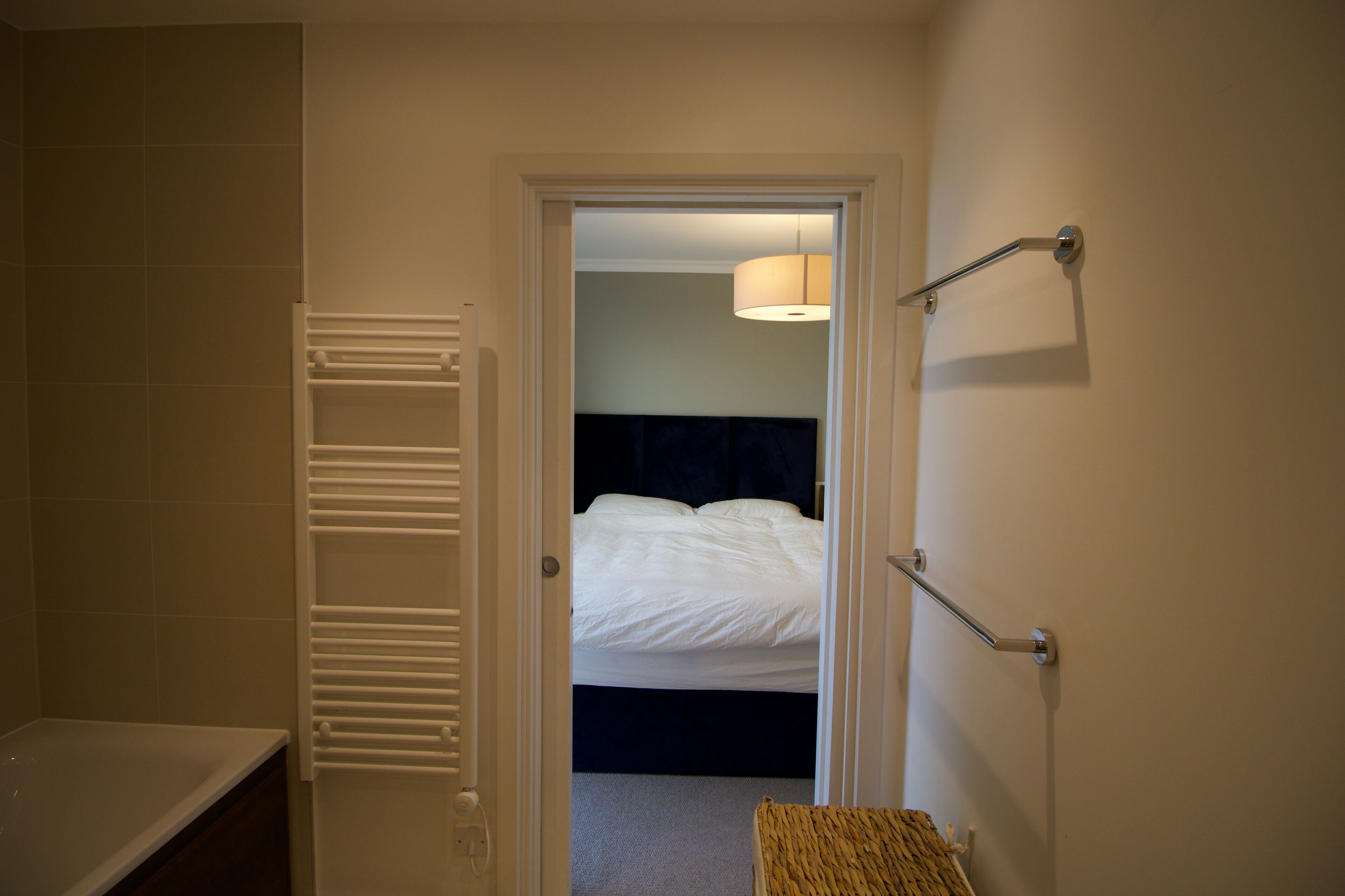 Ein Hotelzimmer mit einem Bett, einer Nachttischlampe, einem Handtuchhalter und einem kleinen Korbwäscheschrank.
