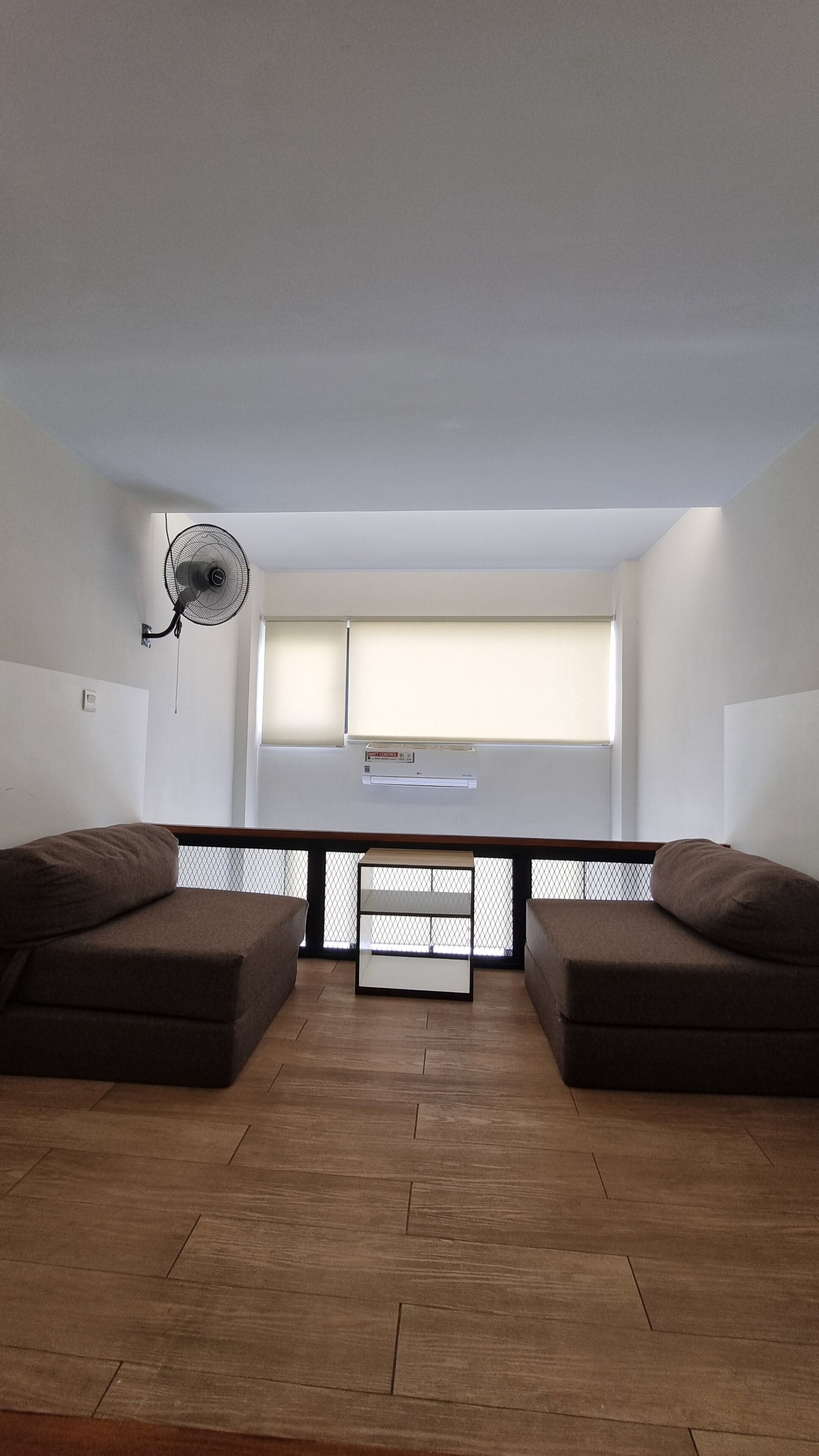 Una habitación con un ventanal grande, un ventilador de techo y dos sofás.