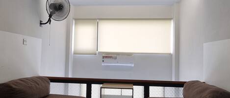 Una habitación con un ventanal grande, un ventilador de techo y dos sofás.