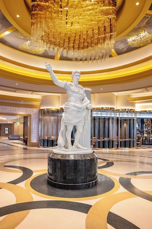 Une statue de marbre dans un hall d’entrée, agrémentée d’un lustre moderne et d’une enseigne Starbucks.