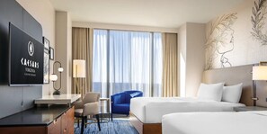 A hotel room with a TV, a desk, two beds, a chair, and a large window with curtains. - Caesars Virginia Hotel & Casino - A Caesars Rewards Destination (Danville)
