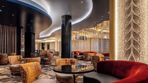A hotel lobby with a modern design, featuring a central column, seating arrangements, and a patterned carpet. - Caesars Virginia Hotel & Casino - A Caesars Rewards Destination (Danville)