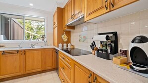 A modern kitchen with wooden cabinets, a built-in oven, and a coffee machine.