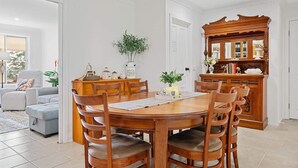 A dining area with a wooden table and chairs, a cabinet with glass doors, and a plant on the wall.