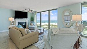 Een woonkamer met een open haard, een bank, een bijzettafeltje en uitzicht op het strand.