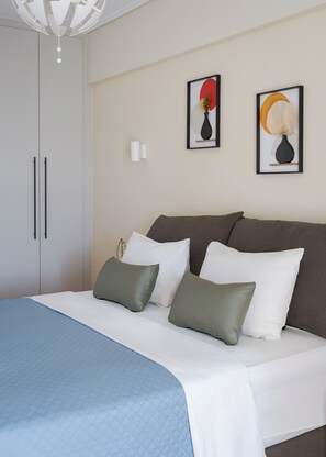 Un dormitorio con cama, almohadas, una mesita de noche, un armario y dos obras de arte colgadas en la pared.