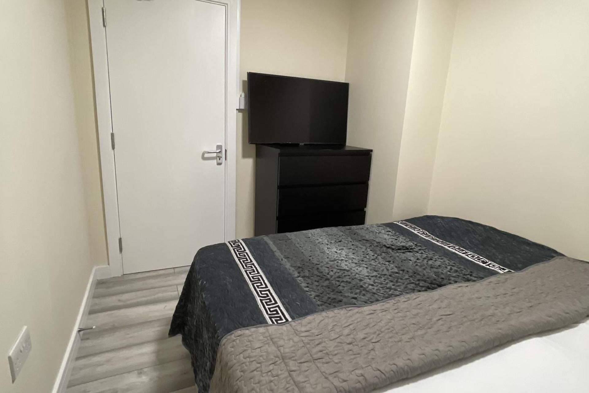Een slaapkamer met een bed, een kaptafel en een televisie op een dressoir.