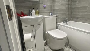 Een moderne badkamer met toilet, wastafel en bad.